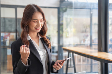 Marketing, Financial, Accounting, Planning, bAsian female entrepreneur in hand holding a smart phone Expressing joy that the company has succeeded in gaining profits from business management.