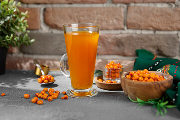 Orange tea on transparent cup. Homemade tea with sea-buckthorn isolation on concrete background....