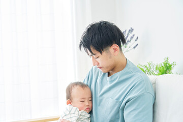 Obraz na płótnie Canvas 家で昼寝をする赤ちゃんを抱っこする父親