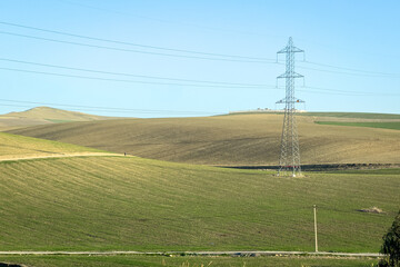 Electricity network poles on a rural area with a green field