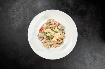 Seafood pasta with vongole, clams, salmon fish and prawns in white plate. Spaghetti marinara with seafood and cheese on dark background. Seafood menu -  pasta in mediterrian  style on black table.