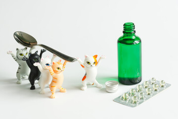 Funny toy kittens carry a teaspoon to an open green bottle with medicinal syrup. Game concept for...