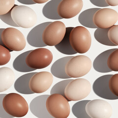 Easter eggs trend pattern with beige gradient colored eggshell, hard Shadow at sunlight, white background. Chicken eggs layout, top view, minimal flat lay, holiday food still life photo