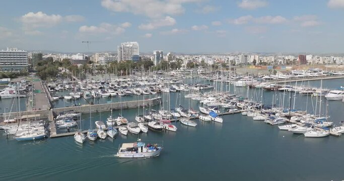 Aerial view of a marina with luxury yachts in Cyprus. Boats moored on the shore of the Mediterranean Sea in a cityscape. High quality 4k footage