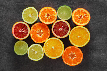 Citrus fruits cut in half, oranges, tangerines, lemons, limes on dark background, top view