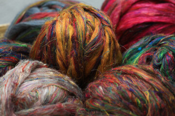 Colourful ball of recycled sari silk textile fibres from India, ready for spinning on a traditional...