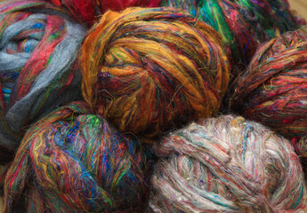 Colourful ball of recycled sari silk textile fibres from India, ready for spinning on a traditional...