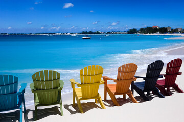 Colorful wooden chairs on white sand Caribbean beach