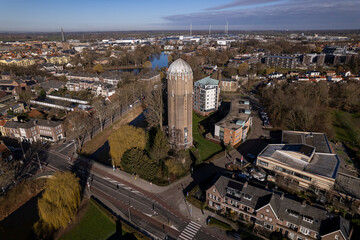 Obraz premium Cityscape of Zutphen with former Dutch brick water tower in now repurposed as a residential home in the foreground Hanseatic town in the background against a blue sky. 