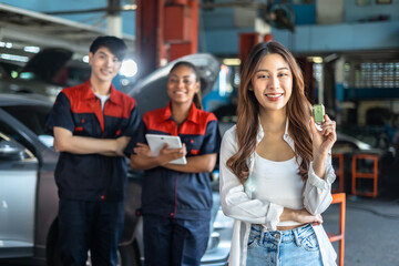 woman receiving her car keys.young engineer auto mechanic in uniform is returning car key to a client, both are smiling.