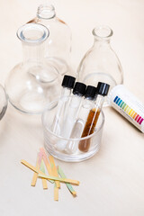 test tubes with liquids and solutions, flasks and indicator papers on light desk