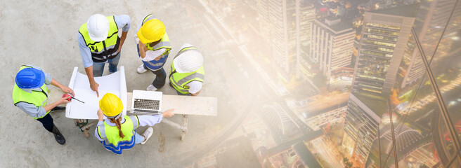 Top view of contractors, engineers and formats team in safety vests with helmets working with...