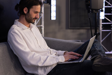 portrait d'un homme qui travaille sur son ordinateur portable, assis dans un sofa