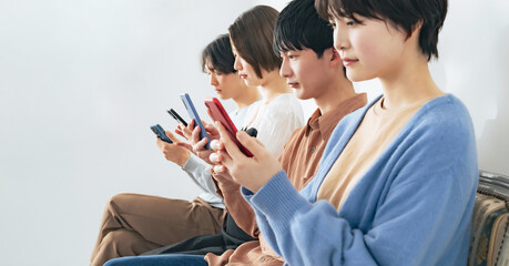並んでスマホを見る若いグループ