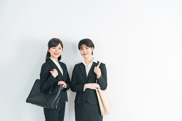 おしゃれなオフィスに立つスーツを着た二人の若い女性　就活生　フレッシャーズ