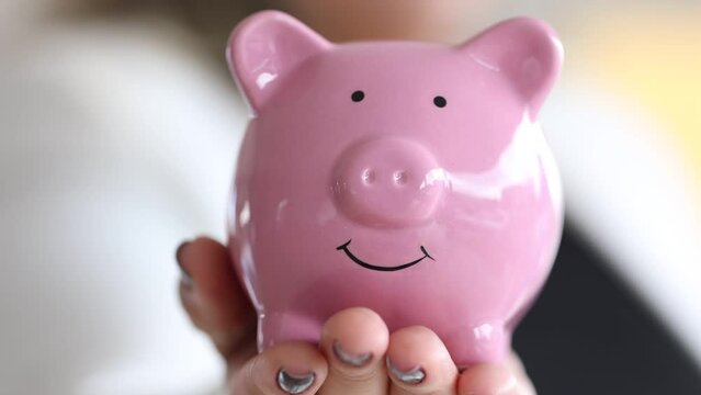 Um mulher de neg&oacute;cios mostrando um cofrinho que est&aacute; em sua m&atilde;o. Finan&ccedil;as, investimentos e economia.