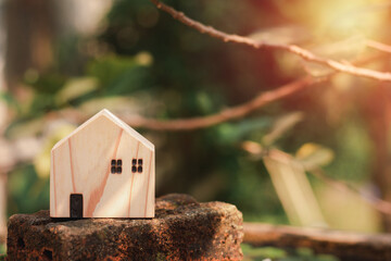 Eco-friendly house concept. The wooden home stands on older brick with a green background, and copy space. Natural sustainable.