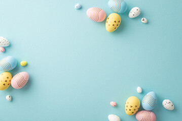 Easter decor concept. Top view photo of composition of pink blue and yellow easter eggs on isolated pastel blue background with copyspace in the middle