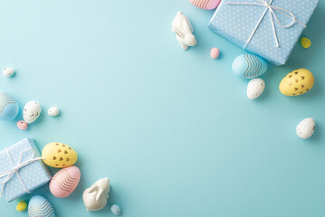 Easter decorations concept. Top view photo of blue gift boxes colorful easter eggs and ceramic bunnies on isolated pastel blue background with blank space