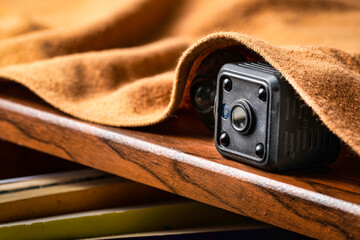 closeup hidden or spy camera under cloth on wooden shelf. Spy or detective or scandal concept.