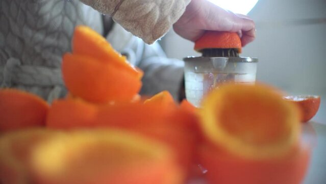 Woman using orange juicer, squeezer, reamer preparing an orange juice at home.