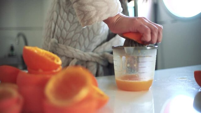 Woman using orange juicer, squeezer, reamer preparing an orange juice at home.
