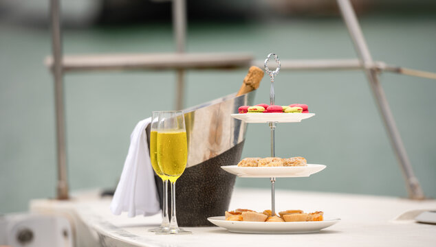 Rich man sleep lying in yacht ship for eat Afternoon tea and champagne . yachting man relax with cake stand decorate catering banquet services with champagne in sea and sunlight