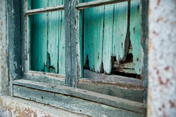 Abandoned place of residence: Decayed green window frame with shutters behind it.