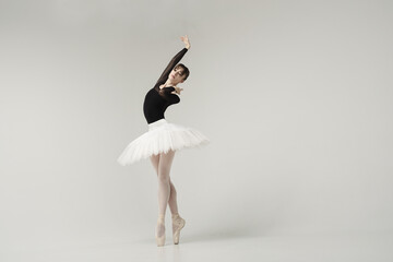 ballerina in a black bodysuit and tutu poses in motion showing ballet elements while standing on...