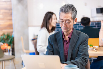 カフェで仕事をする中年男性