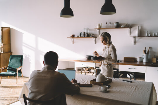 Senior couple spending time together in kitchen while preparing breakfast