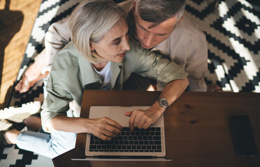 Elderly couple using netbook sitting on floor