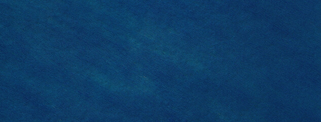 Texture of a navy blue felt background with denim spots of fabric, macro. Structure of woolen ultramarine textile