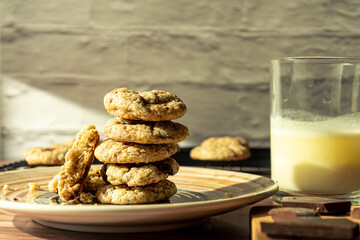 Detail of a column of chocolate chip cookies on a plate with a batch, illuminated by the light from a window.