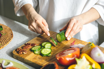 A woman cuts vegetables for a salad, close-up.