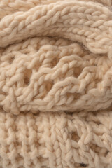 A fragment of beige knitted fabric, knitted from white sheep wool.