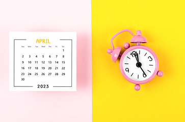 The April 2023 Monthly calendar for 2023 year with pink colour alarm clock on beautiful background.