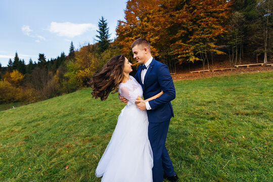 The bride and groom are dancing in nature looking at each other