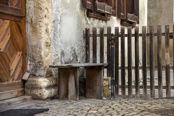 old wooden bench and gate, at the entrance of an old house in the swiss alps