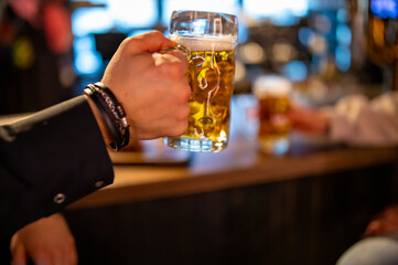 man holds a glass of beer in his hand at the bar or pub