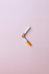 Broken cigarette and tobacco on a pink background. Smoking cessation concept