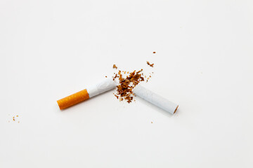 Broken cigarette on a white surface with a filter on the left, top view, horizontal