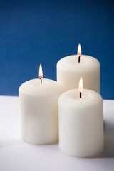 Fototapeta na wymiar three burning candles on a blue background