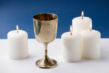 beautiful christian chalice surrounded by candles and blue background