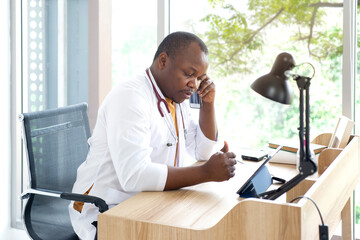 African male doctor talking smartphone with patient,    consulting patients online on smartphone,...
