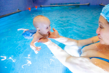 Adorable baby girl enjoying swimming in a pool with her mother early development class for infants...