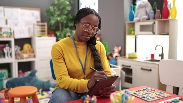 African woman working as teacher with tablet at kindergarten