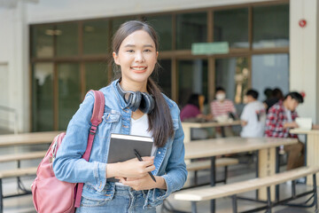 Beautiful student asian woman with backpack and books outdoor. Smile girl happy carrying a lot of book in college campus. Portrait female on international Asia University. Education, study, school