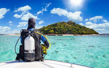 A scuba diver in his diving gear sits in front of a boat and enjoys the view of the tropical...