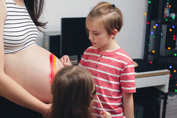 Baby birth expecting time and belly painting. Happy kids painting pregnant belly their mother.